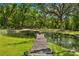 Picturesque pond with a wooden dock, surrounded by lush greenery and mature trees at 13700 Sw 108Th Ln, Dunnellon, FL 34432