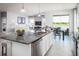 Modern kitchen featuring granite counters, an island with seating, a dining table, and adjacent living room at 1556 Covey Rise Ter, Winter Haven, FL 33884