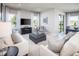 Bright and airy living room with white sofas, a gray ottoman, a TV, and natural light from large windows at 1556 Covey Rise Ter, Winter Haven, FL 33884