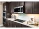 Close up on a kitchen featuring stainless appliances, sleek dark cabinets, granite countertops and stylish backsplash at 3186 Tiger Palm Way, New Smyrna Beach, FL 32168