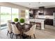 Open kitchen and dining area with wood floors, dark cabinets, granite countertops, and large windows at 3190 Tiger Palm Way, New Smyrna Beach, FL 32168