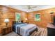 Cozy bedroom featuring natural wood paneling, two windows, ceiling fan, and wood-look flooring at 2955 Se 156Th Place Rd, Summerfield, FL 34491