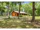 Charming log cabin home featuring a covered porch and surrounded by lush greenery at 2955 Se 156Th Place Rd, Summerfield, FL 34491