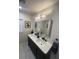 Stylish bathroom boasts double sinks, modern fixtures, and chic black-framed mirror at 601 Lantern Ln, Orange City, FL 32763