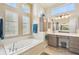 Bright bathroom with a soaking tub, vanity with mirrors, and large windows at 27223 Nostalgia Dr, Leesburg, FL 34748
