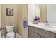 Half bathroom with a toilet, vanity with cabinet storage, large mirror, and decorative flowers at 27223 Nostalgia Dr, Leesburg, FL 34748