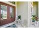 Charming front porch with double doors, a small table with two chairs, and colorful potted plants at 27223 Nostalgia Dr, Leesburg, FL 34748