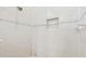 Shower featuring white tile walls, a shower head, a recessed shelf and leaf-patterned detail at 27223 Nostalgia Dr, Leesburg, FL 34748