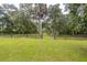 View of the lush green front yard with mature trees and a gated fence at 3341 Se 45Th St, Ocala, FL 34480