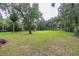 Expansive front yard featuring mature trees, lush green grass, and a wooden fence in a serene, wooded setting at 3341 Se 45Th St, Ocala, FL 34480
