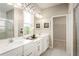 Bright bathroom with double sinks, white vanity, framed mirrors, a glass enclosed shower and neutral decor at 1278 Whispering Ln, Minneola, FL 34715