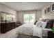Comfortable main bedroom with large window, dresser, chair and plush patterned bedding at 1278 Whispering Ln, Minneola, FL 34715