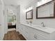 Bright, modern bathroom featuring double sinks, white cabinets, quartz counters, and wood floors at 9783 Sw 206Th Court Rd, Dunnellon, FL 34431