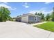 Side view of the home featuring a concrete driveway, gray exterior, manicured lawn, and attached garage at 9783 Sw 206Th Court Rd, Dunnellon, FL 34431