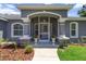 Close-up of a charming front porch with decorative columns, potted plants, and a welcoming entrance at 9783 Sw 206Th Court Rd, Dunnellon, FL 34431