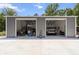 Interior view of a large garage or shed with open doors, a vehicle lift, and parked vehicles at 9783 Sw 206Th Court Rd, Dunnellon, FL 34431