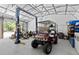 View of a lift, golf cart, and other equipment inside a large garage or shed with concrete floors at 9783 Sw 206Th Court Rd, Dunnellon, FL 34431