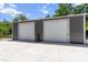 Detached two-bay garage featuring a concrete slab, gray exterior, and white doors at 9783 Sw 206Th Court Rd, Dunnellon, FL 34431