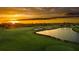 Dramatic sunset view of a scenic golf course, featuring a tranquil pond, green grass, and bunkers at 3307 Grande Heron Dr, St Cloud, FL 34773