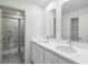 A bathroom with double sinks, white cabinets, quartz countertops, and a tiled glass shower at 5240 Luisa Ct, St Cloud, FL 34771
