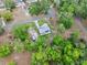 Top-down aerial view of home nestled within verdant trees, revealing driveway and nearby homes in this charming community at 1161 Cr 443, Lake Panasoffkee, FL 33538