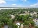 An aerial view showcases the property and nearby lake, surrounded by lush greenery and homes under a partly cloudy sky at 1161 Cr 443, Lake Panasoffkee, FL 33538