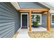Welcoming entryway with a modern black door, wooden beam accents, a convenient bench, and attractive landscaping at 1161 Cr 443, Lake Panasoffkee, FL 33538