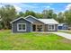 Inviting single-story house with gray siding, a metal roof, well kept lawn, and a matching storage shed in the backyard at 1161 Cr 443, Lake Panasoffkee, FL 33538