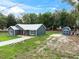 Exterior of new home with light metal roof, blue paint, and blue shed with concrete slab at 1161 Cr 443, Lake Panasoffkee, FL 33538