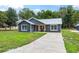 Charming residence with gray siding and a metal roof, complemented by a well-kept lawn and a concrete driveway at 1161 Cr 443, Lake Panasoffkee, FL 33538