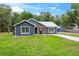 Charming home with gray siding, a metal roof, and a well-manicured lawn featuring a driveway and a storage shed at 1161 Cr 443, Lake Panasoffkee, FL 33538