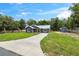 Lovely home featuring gray siding, a metal roof, and a well-maintained front yard with a concrete driveway and storage shed at 1161 Cr 443, Lake Panasoffkee, FL 33538