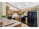 Charming kitchen featuring warm wood cabinets, stone countertops, and modern black appliances at 1161 Cr 443, Lake Panasoffkee, FL 33538