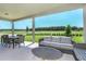 Covered patio with outdoor dining and seating area overlooking a beautiful green space at 136 Venetian Palms Blvd, New Smyrna Beach, FL 32168
