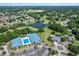 Aerial view showcases a neighborhood with golf course, a large pond, community buildings and pool at 8596 Sw 108Th Place Rd, Ocala, FL 34481