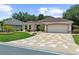 Attractive home with a well-maintained lawn, stone-paved driveway, and mature landscaping at 1424 Figueroa St, The Villages, FL 32162