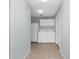 Hallway view of the laundry room with tiled floor, washer and dryer, white cabinets, and refrigerator at 1424 Figueroa St, The Villages, FL 32162