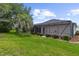 View of the screened-in patio overlooking the landscaped backyard with lush green grass and palm trees at 1424 Figueroa St, The Villages, FL 32162