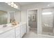Bright bathroom featuring double sink vanity, large mirror, decorative decor, and a glass enclosed shower at 454 Hammock Oaks Blvd, Lady Lake, FL 32159