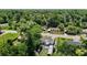 Aerial view of a home with solar panels surrounded by lush trees, street access, and a well-maintained lawn at 801 Nw 16Th Ct, Ocala, FL 34475