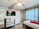 The bedroom features light-gray walls, carpet, a ceiling fan, and a dresser with a wall-mounted television at 801 Nw 16Th Ct, Ocala, FL 34475