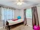 The bedroom features light-gray walls, a ceiling fan, two windows with dark curtains, and carpet at 801 Nw 16Th Ct, Ocala, FL 34475