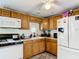 Practical kitchen with wood cabinets, white appliances, and a window over the sink area at 801 Nw 16Th Ct, Ocala, FL 34475