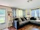 Cozy living room with a comfortable sectional sofa, decorative curtains, and wood flooring at 801 Nw 16Th Ct, Ocala, FL 34475