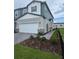 View of a two-story home showcasing its green siding, two-car garage, and nicely landscaped front yard at 2453 Magnolia Reserve Rd, Ocoee, FL 34761