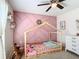bedroom with a pink accent wall, wood laminate flooring, and a house-shaped bed frame at 12396 Sw 64Th Street Rd, Ocala, FL 34481