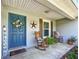 Inviting front porch with rocking chairs and a blue front door with decorative wreath and 'Welcome' sign at 12396 Sw 64Th Street Rd, Ocala, FL 34481