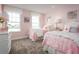 Charming pink bedroom with twin beds, soft carpeting, and bright natural light from large windows at 1722 Upland Ln, Winter Haven, FL 33884