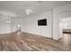 Spacious living room with hardwood floors, ceiling fan, and a mounted television at 3315 Dzuro Dr, Oxford, FL 34484