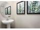 Elegant powder room with a pedestal sink, round mirror, and decorative botanical wall art at 2307 Incandescent Way, South Daytona, FL 32119